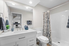 A modern bathroom with a white vanity, a toilet, and a shower.