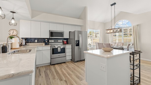 A modern kitchen with white cabinets, stainless steel appliances, and a wooden floor. - Golf Views • Central Branson • 3 King Suites (Branson)