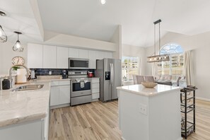Uma cozinha moderna com armários brancos, eletrodomésticos de aço inoxidável e piso de madeira.