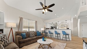 A modern living room with a brown sofa, a round coffee table, and a ceiling fan. - Golf Views • Central Branson • 3 King Suites (Branson)