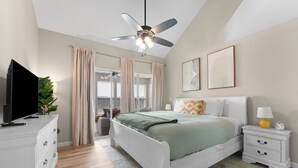 A bedroom with a bed, a nightstand, a TV, a ceiling fan, and a window with curtains. - Golf Views • Central Branson • 3 King Suites (Branson)