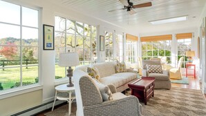A sunlit room with a sofa, chairs, a table, and a ceiling fan. - Farlea: Classic Country Charm Minutes from UVA (Charlottesville)