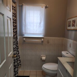 A bathroom with a toilet, a shower, and a window with a curtain. - Spacious 6BR Newark Retreat near Penn Station - Free Parking-Sleeps 16+ (Newark)