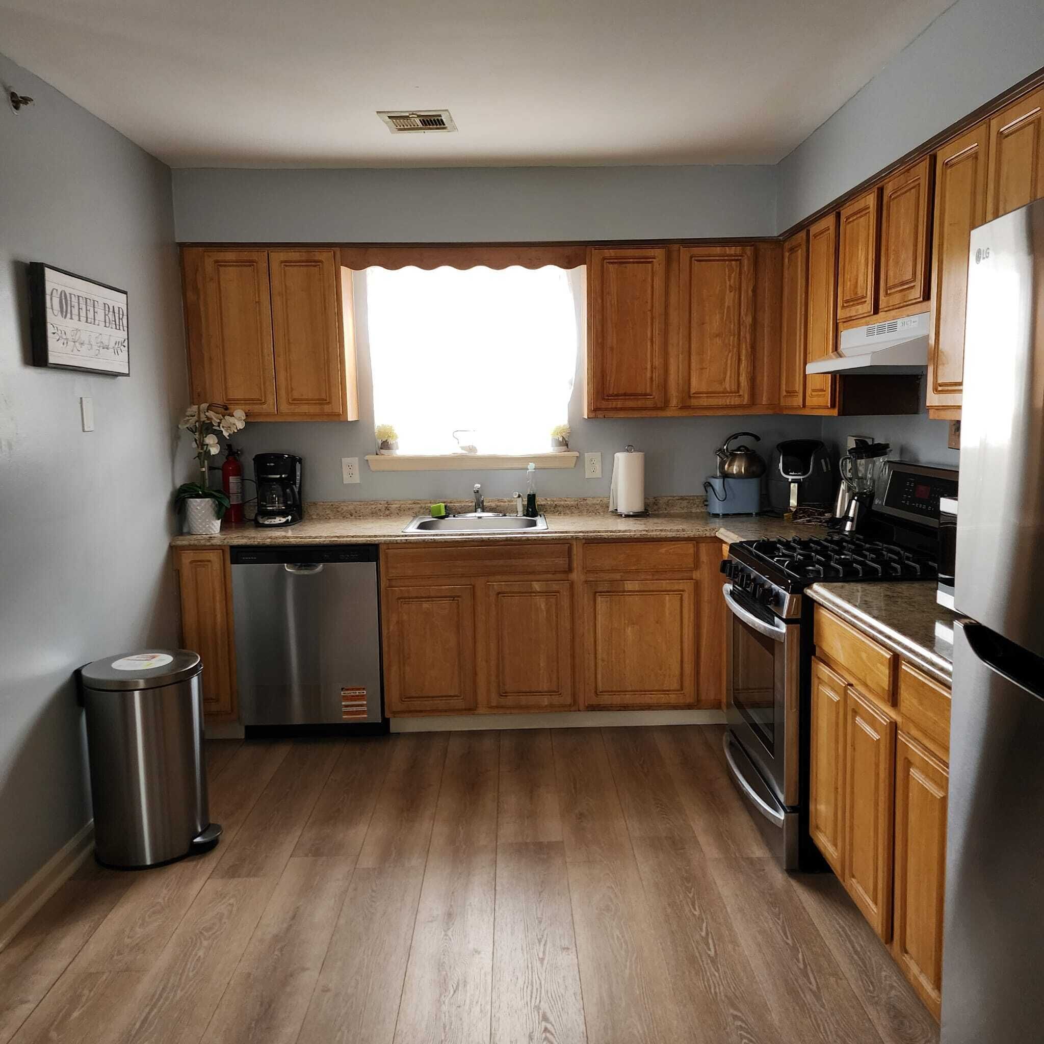A kitchen with wooden cabinets, a stainless steel dishwasher, a sink, a stove, and a refrigerator.