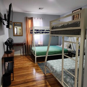 A dormitory room with bunk beds, a desk, a chair, a fan, and a mirror. - Spacious 6BR Newark Retreat near Penn Station - Free Parking-Sleeps 16+ (Newark)