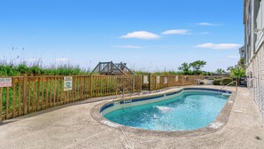 A swimming pool with a wooden fence, a wooden bridge, and a sign indicating no feeding of birds. - Cozy Oceanfront Condo - 2 Bedroom Sleeps 5 + Pool (Surfside Beach)