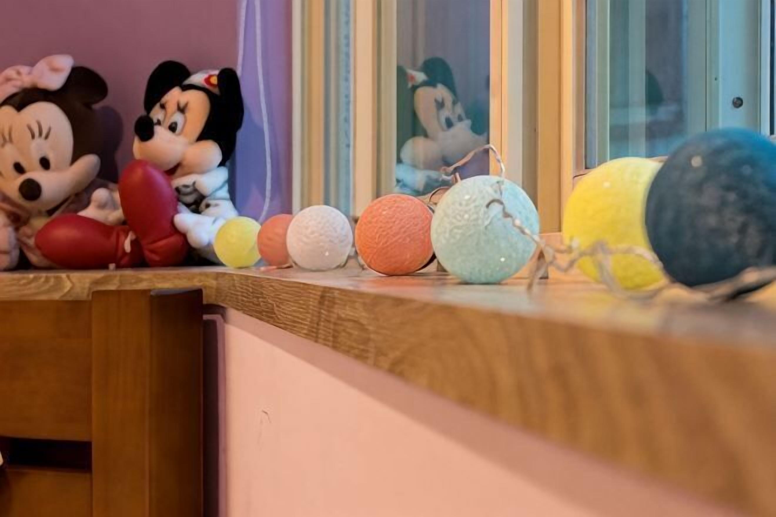 Mickey en Minnie Mouse beeldjes op een houten oppervlak met kleurrijke ballen.