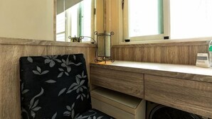 A room with a wooden desk, a chair with a floral pattern, a mirror, and a window with blinds. - Hualien Yi Jing BnB (Hualien)