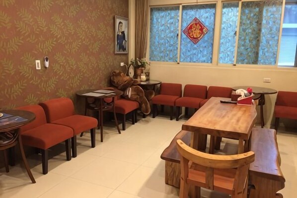 A room with a wooden dining table, red sofas, and a patterned wall. - Hualien Yi Jing BnB (Hualien)