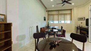 A dining area with a round table, chairs, a ceiling fan, and a window with blinds. - Hualien Yi Jing BnB (Hualien)