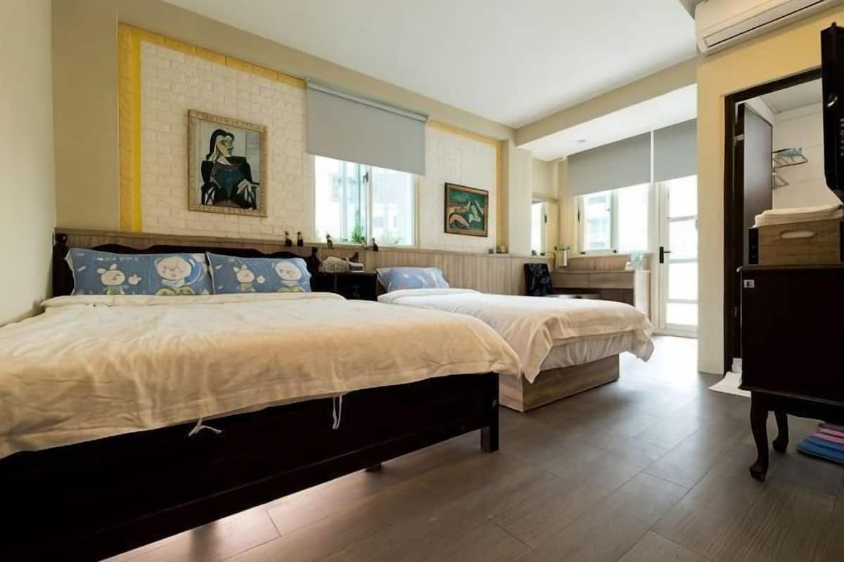 A bedroom with two beds, a dresser, and a window.