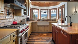 A kitchen with a stove, oven, and large windows offering a view of a snowy landscape. - Fore Seasons Lodge | Pole Creek Golf Course | Private Hot Tub | Sleeps 16! (Tabernash)