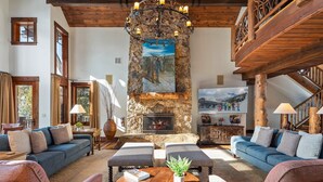 A spacious living room with a stone fireplace, wooden beams, and comfortable seating. - Fore Seasons Lodge | Pole Creek Golf Course | Private Hot Tub | Sleeps 16! (Tabernash)