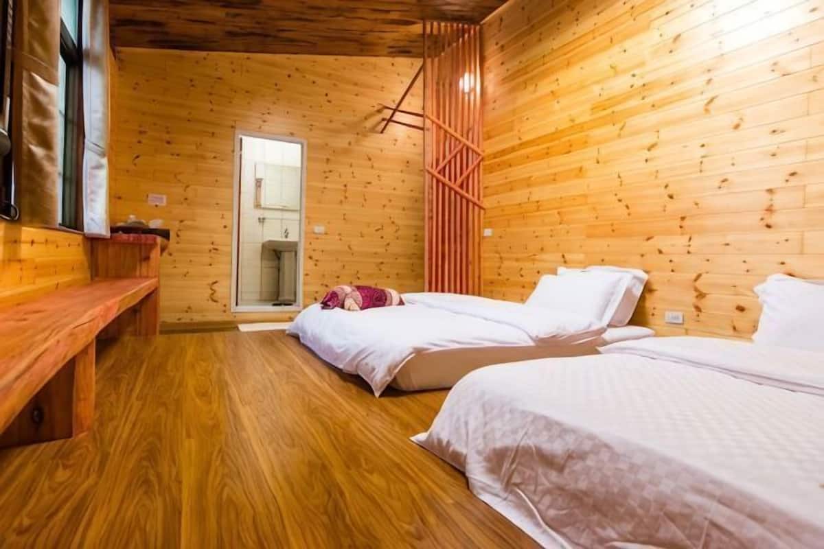 A wooden cabin-style room with two beds, a bench, and a wooden floor.