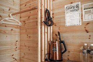 A wooden cabin interior with a hanging coat rack, a kettle, and a menu on the wall. - Alishan Sunrise B&B (Chiayi County)