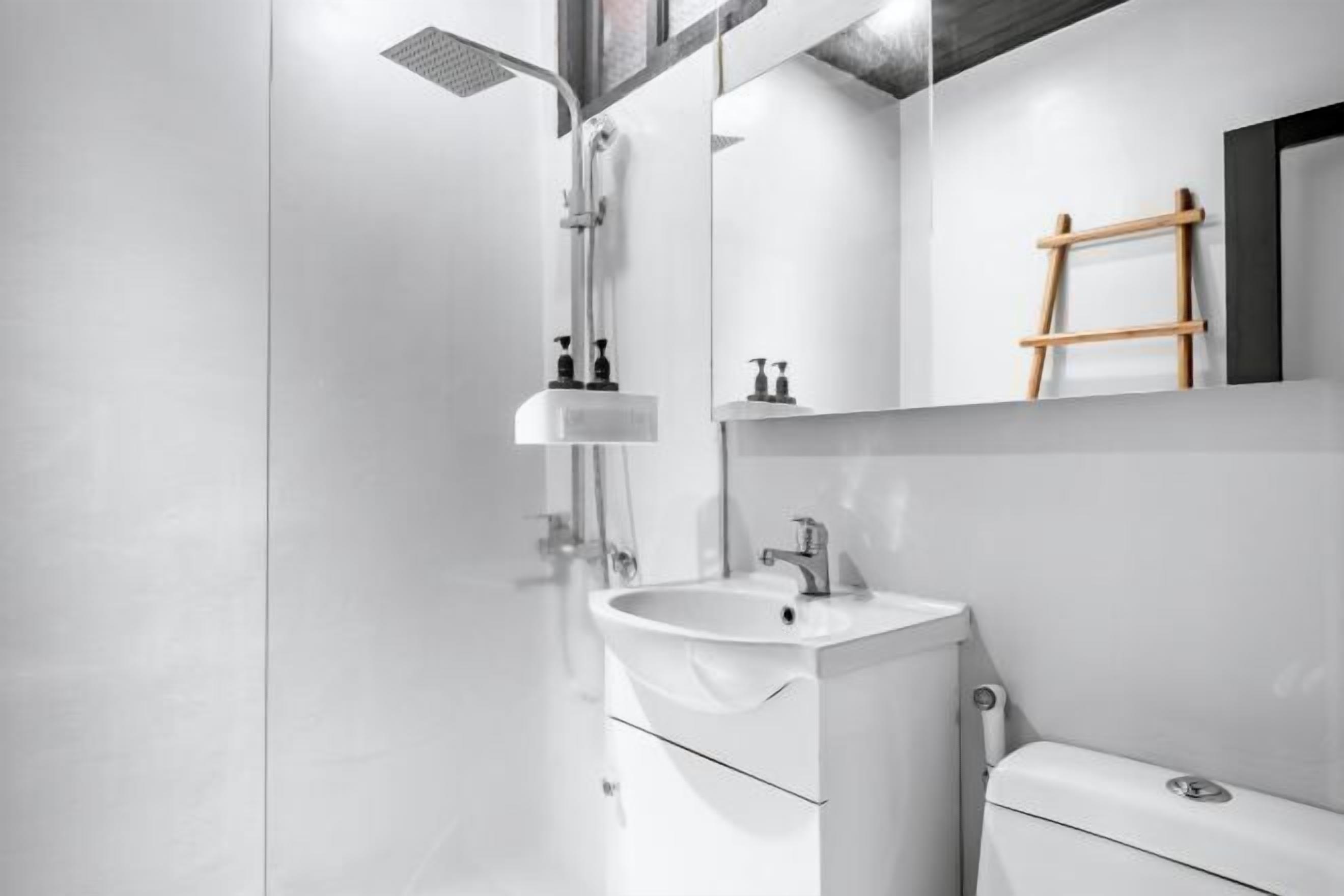 A modern bathroom with a glass shower enclosure, a white sink, and a toilet.