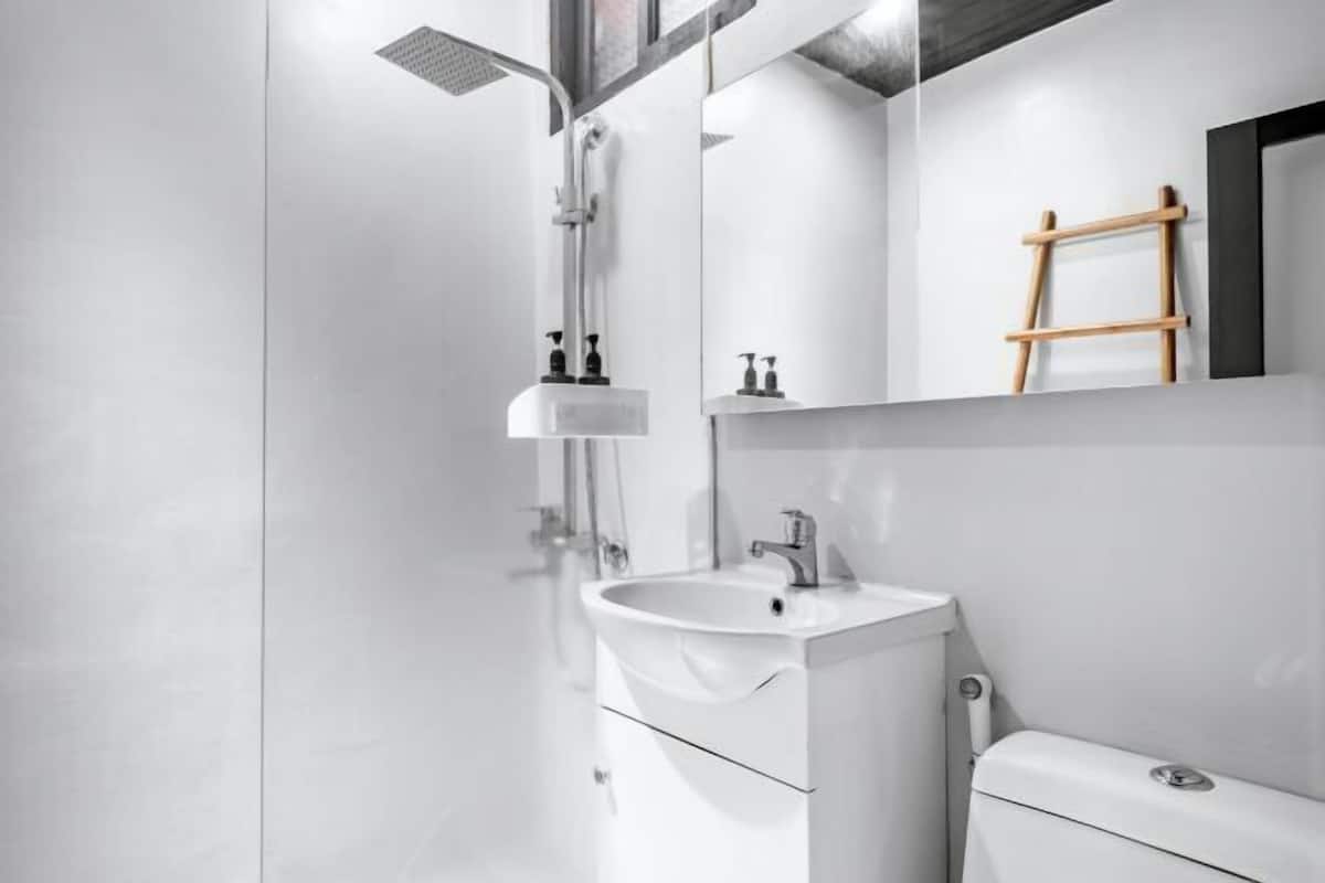 A modern bathroom with a glass shower enclosure, a white sink, and a toilet.