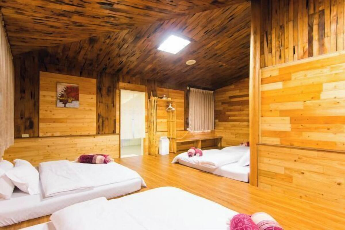 A wooden cabin room with two beds, a bench, and a small table.