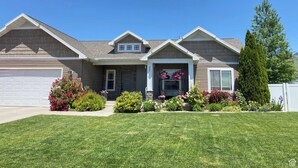 A two-story house with a garage, a front porch with potted plants, and a well-maintained lawn. - Spacious retreat, sleeps 18 guests comfortably, theater and game room  (Smithfield)