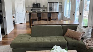 A modern kitchen with white cabinets, stainless steel appliances, and a central island with bar stools. - Spacious retreat, sleeps 18 guests comfortably, theater and game room  (Smithfield)