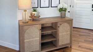 A wooden console table with woven baskets, a lamp, and a small plant. Behind it, there are nine framed signs with various messages. - Spacious retreat, sleeps 18 guests comfortably, theater and game room  (Smithfield)
