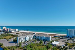 A beachfront hotel with multiple buildings, a parking lot, and a view of the ocean. - Ground-Floor Retreat | Steps to Beach, Pool & Fitness Center | BEACHBALL PROPERTIES (Orange Beach)