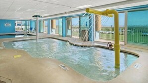 An indoor swimming pool with a yellow water feature, clear glass walls, and a view of the outside. - Stunning 10th-Floor 1-Bedroom Oceanview Condo (Myrtle Beach)