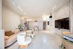 A spacious living area with a sofa, coffee table, and TV. - Secretpath Bed and Breakfast (Pingtung)