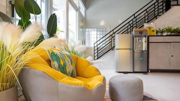 Una cocina moderna con un sofá gris, un pequeño otomaní y una escalera que conduce a un nivel superior.