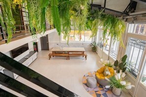 Un interior moderno con una escalera, una zona de comedor y plantas colgantes.