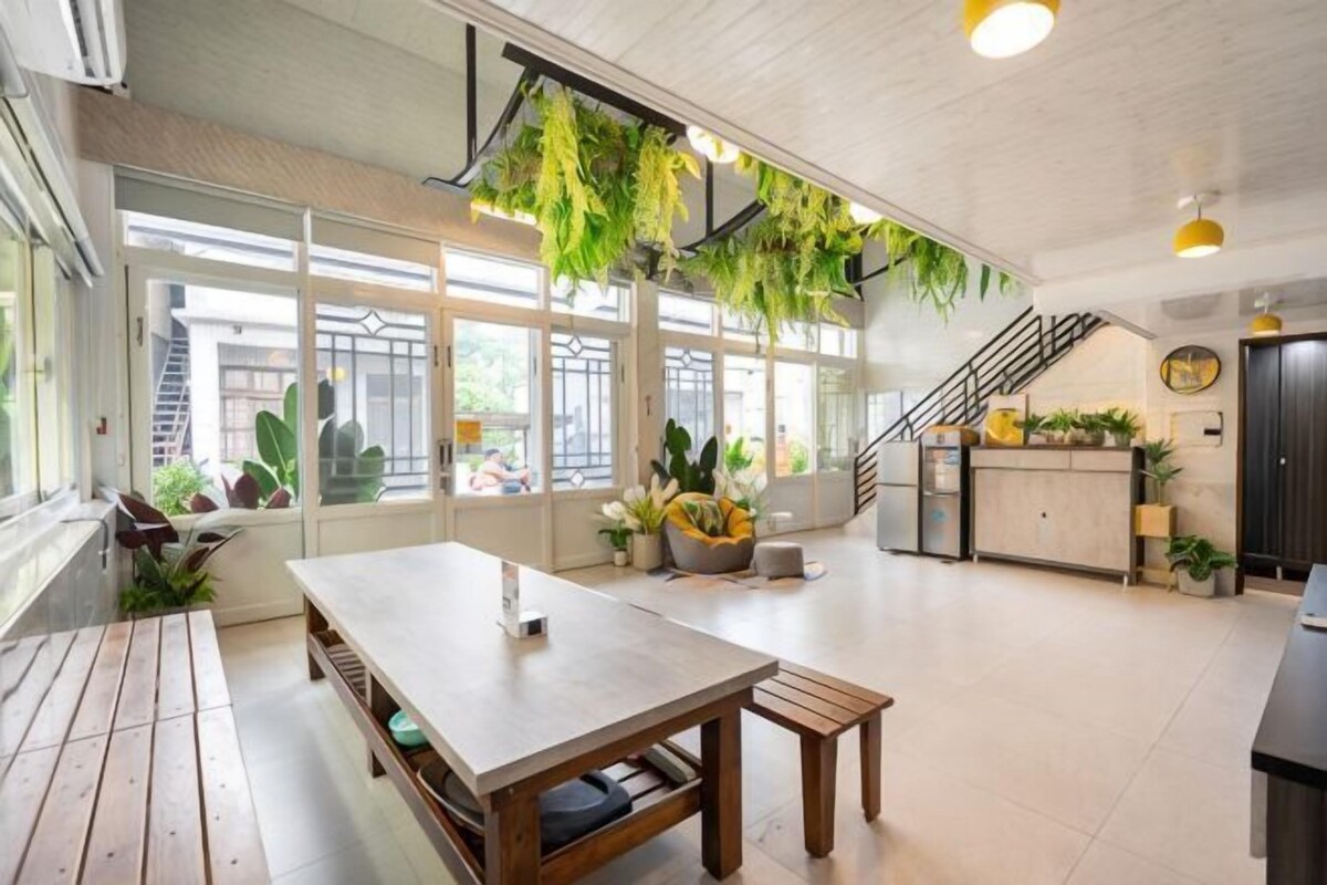 A spacious room with a wooden table, a bench, and a staircase leading to an upper level.
