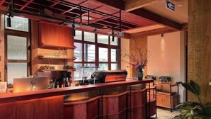 A bar area with wooden furniture, a large window, and a plant. - The Pink Boutique Hotel (Dalat)