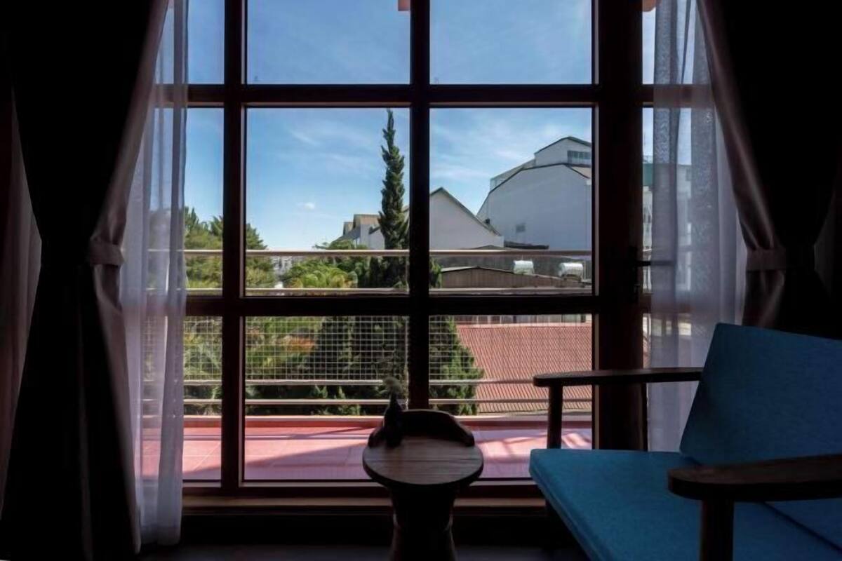 A room with a large window, a blue chair, and a small table.