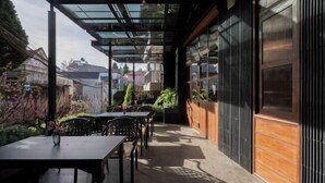 An outdoor patio with tables and chairs, a glass roof, and a view of the surrounding neighborhood. - The Pink Boutique Hotel (Dalat)