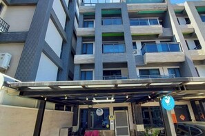 A multi-story building with a covered entrance and a blue sign. - Dolphin B&B (Pingtung)