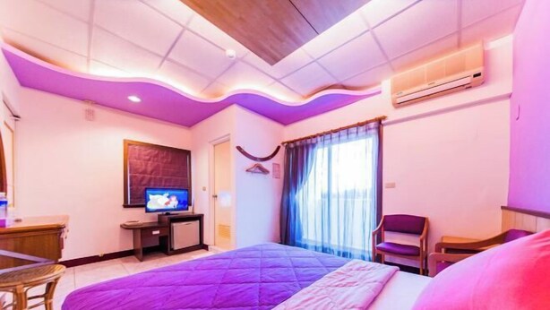 Ein Hotelzimmer mit Bett, Fernseher, Schreibtisch und Stuhl.