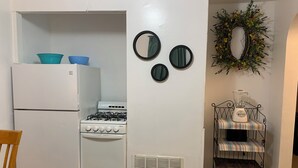 A compact kitchen with a refrigerator, stove, and a small dining table. - Beach Side Studio #2 - Pet Friendly, WiFi, Off-Street Parking, Large Smart TV (Norfolk)
