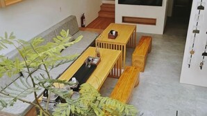 A living room with a sofa, a coffee table, and a bench. There is a plant in the corner and a wall-mounted shelf. - Wuzheng Wood hall (Chiayi County)