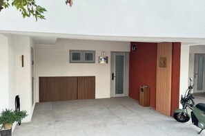 A modern building with a concrete floor, a wooden bench, a door, and a motorcycle parked outside.