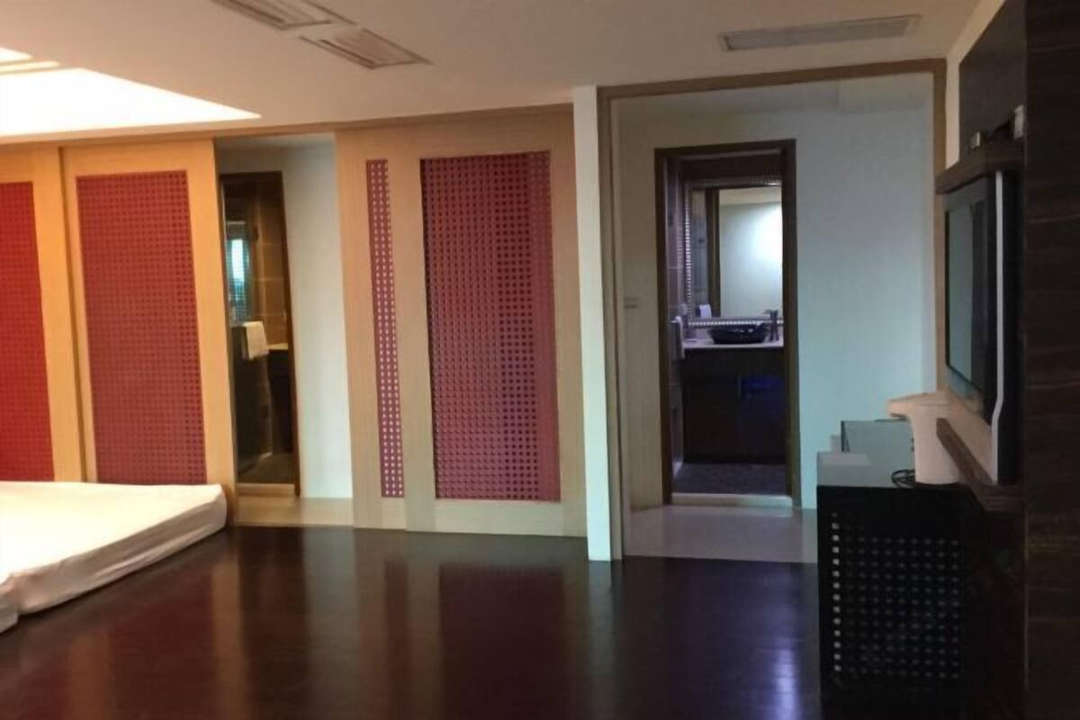 Una habitación de hotel con cama, televisión, escritorio y puerta que da al baño.