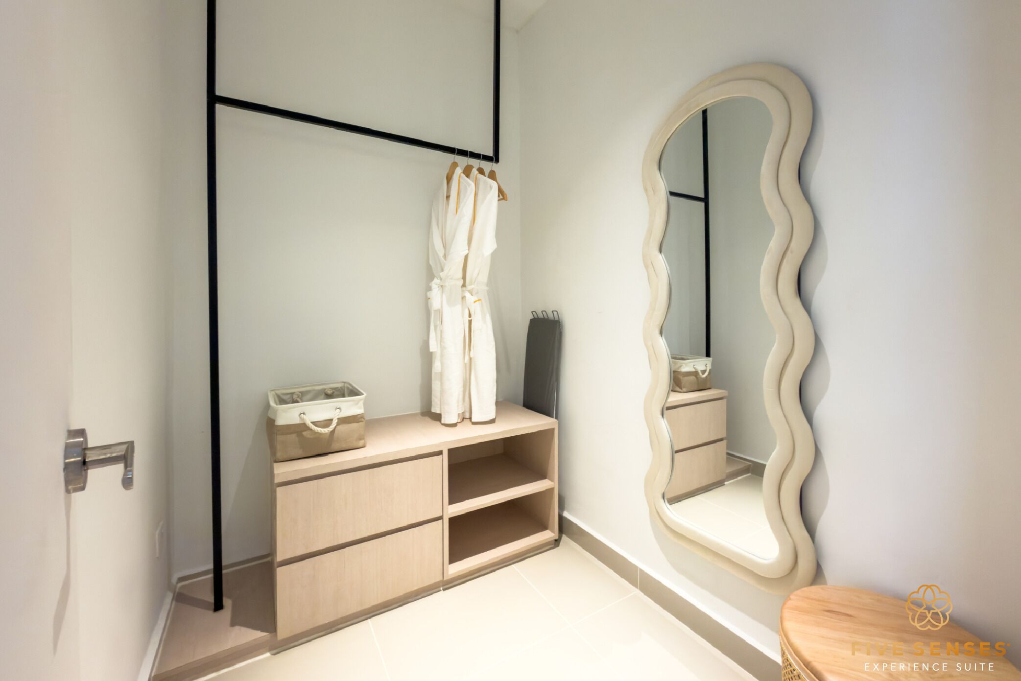 A bathroom with a wooden vanity, a mirror with a wavy frame, and a wooden stool.