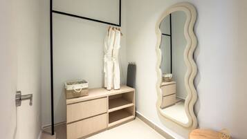 A bathroom with a wooden vanity, a mirror with a wavy frame, and a wooden stool.