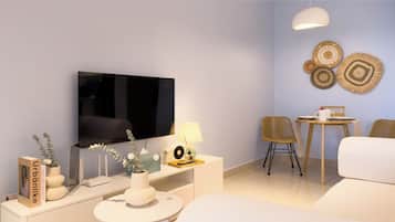 A modern living room with a flat-screen TV, a white sofa, a small round table, and two chairs.
