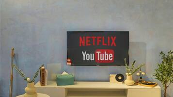 Un téléviseur fixé au mur affiche les logos de Netflix et de YouTube.
