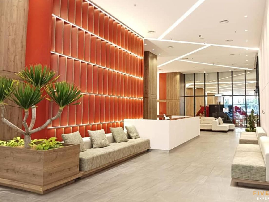 Una hall d'albergo moderna con reception, area salotto e un'ampia finestra che offre vista sull'interno.