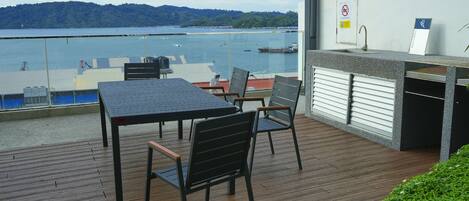 Balkon med et bord og stole med udsigt over vand, et vaskerum og et skilt, der angiver røgfri zone.