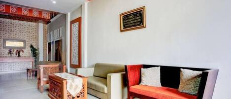 A hotel lobby with a reception desk, a sofa, and a decorative wall panel.