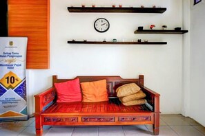A traditional wooden sofa with cushions, a wall clock, and shelves with decorative items. - Dancenter Kuta Alam Near Masjid Oman Al-Makmur (Kuta Alam)
