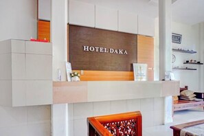 A reception area with a wooden reception desk, a white wall, and a sign that reads 'HOTEL DAKA'. - Dancenter Kuta Alam Near Masjid Oman Al-Makmur (Kuta Alam)