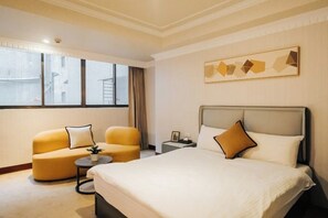 A hotel room with a bed, two armchairs, a small table, a nightstand, and a window with curtains. - Meworld Hotel-Sanchong (New Taipei City)